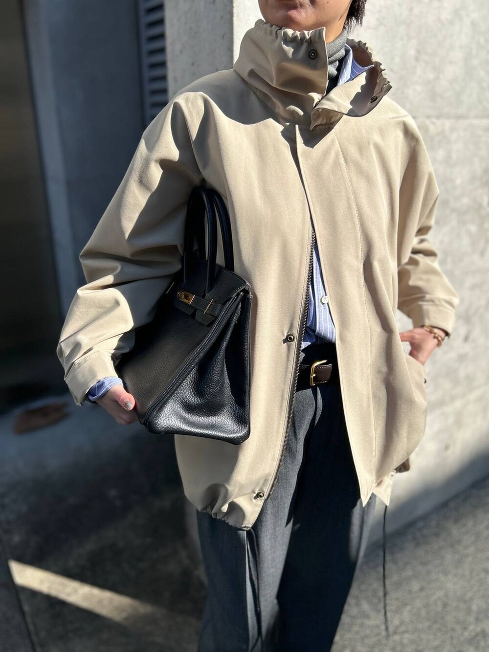 グレー系のニット/セーター、ブルー系のシャツ/ブラウス、グレー系のスラックスを着用したレディースの冬コーディネートの6枚目の写真