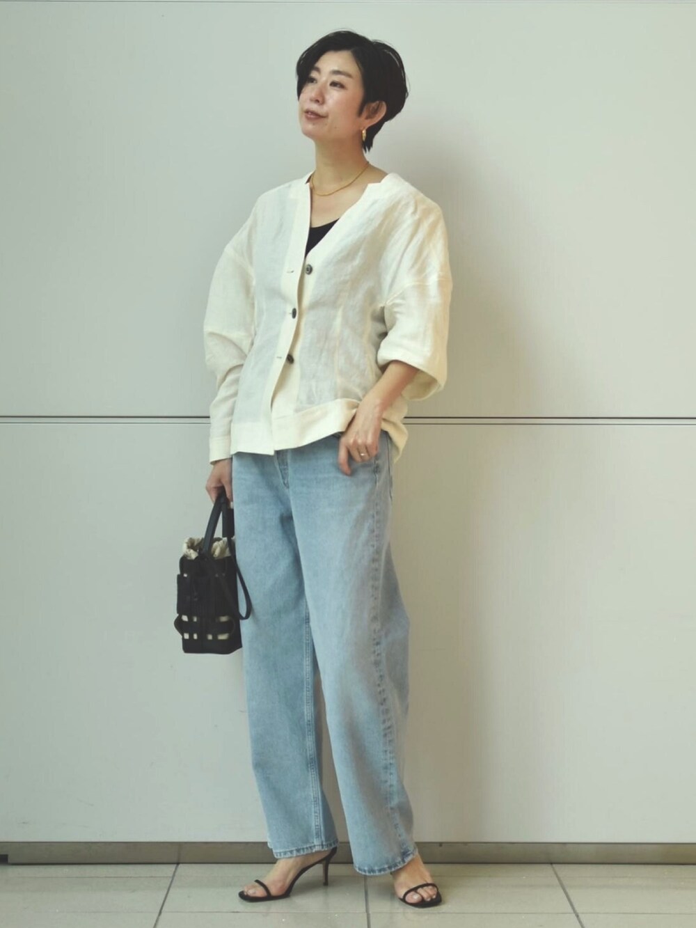 ブルー系のデニムパンツ、ホワイト系のシャツ/ブラウス、ブラック系のタンクトップを着用したレディースの春コーディネートの2枚目の写真