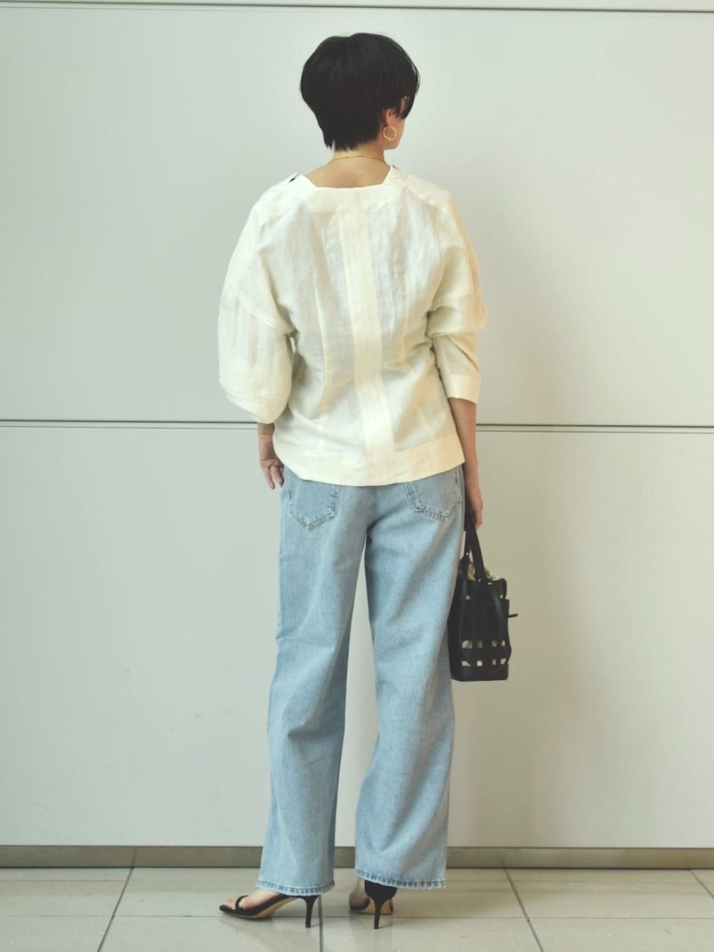 ブルー系のデニムパンツ、ホワイト系のシャツ/ブラウス、ブラック系のタンクトップを着用したレディースの春コーディネートの3枚目の写真