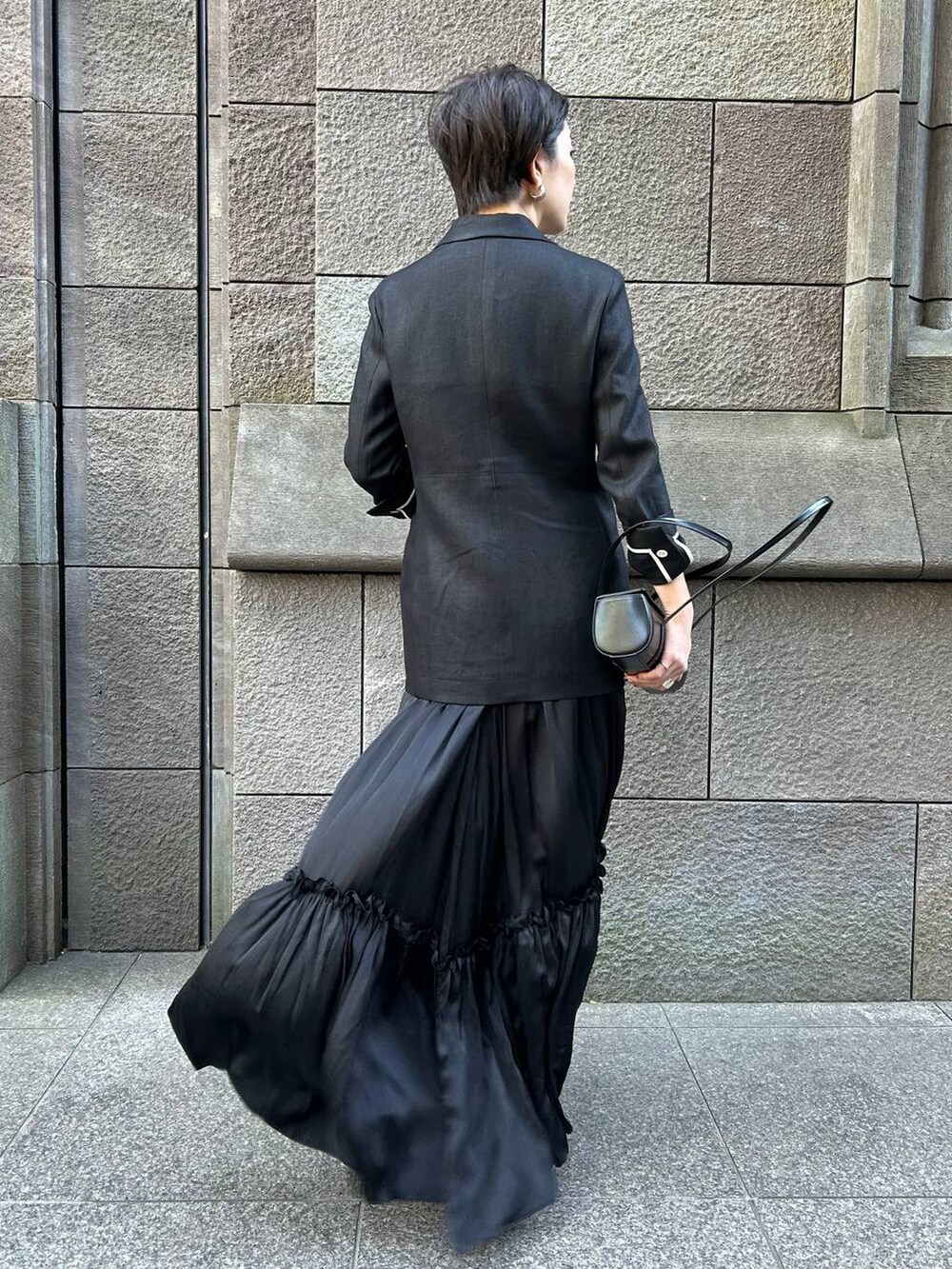 ベージュ系のタンクトップ、ブラック系のサンダル、ブラック系のテーラードジャケットを着用したレディースの冬コーディネートの4枚目の写真