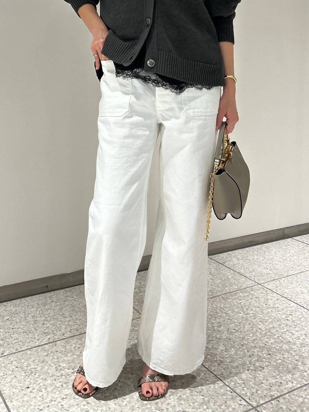 グリーン系のカーディガン/ボレロ、ホワイト系のデニムパンツ、グレー系のナイロンジャケットを着用したレディースの春コーディネートの8枚目の写真