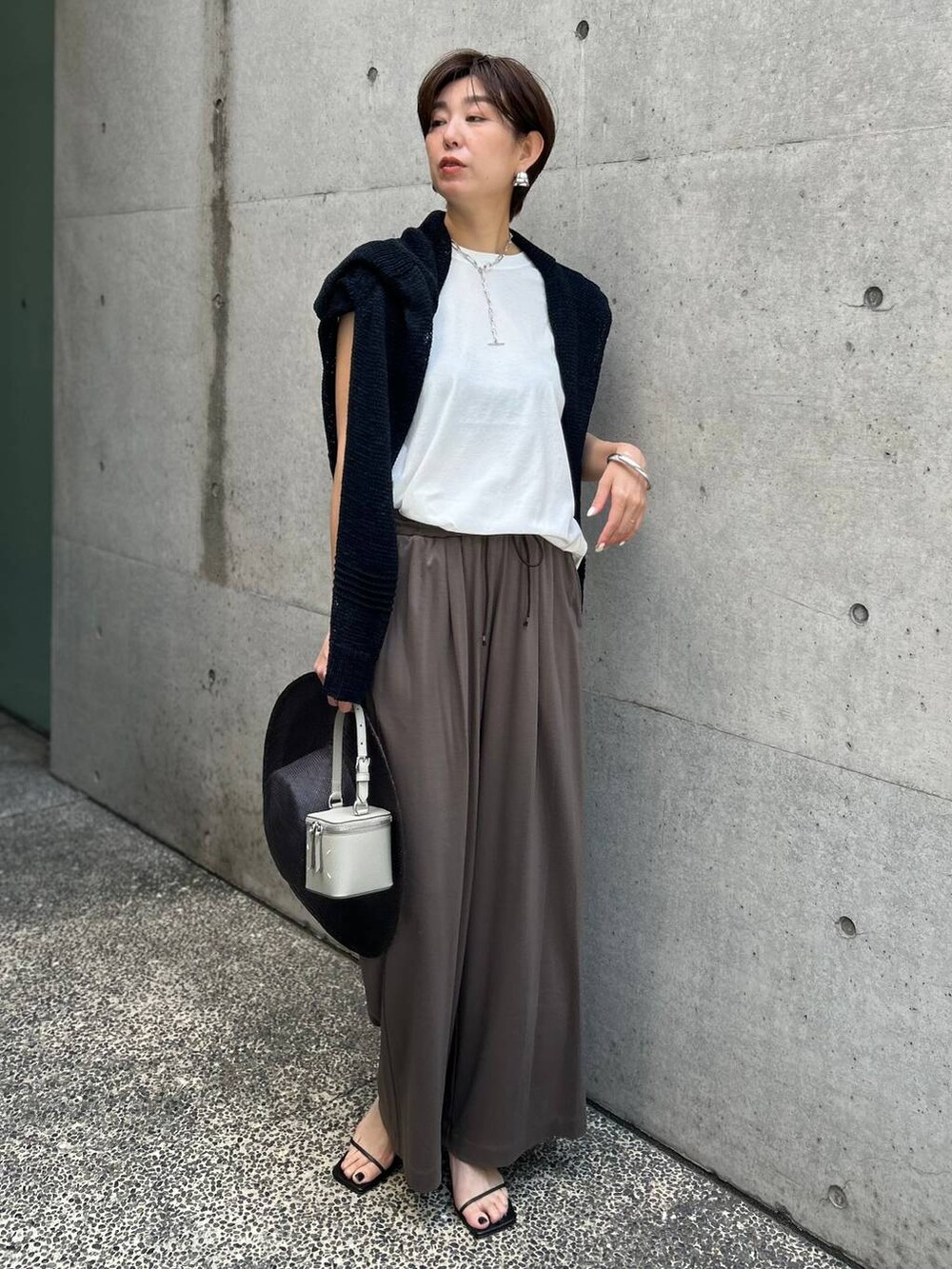 ホワイト系のTシャツ/カットソー、ブラック系のアンサンブル、ブラック系のサンダルを着用したレディースの春コーディネートの2枚目の写真