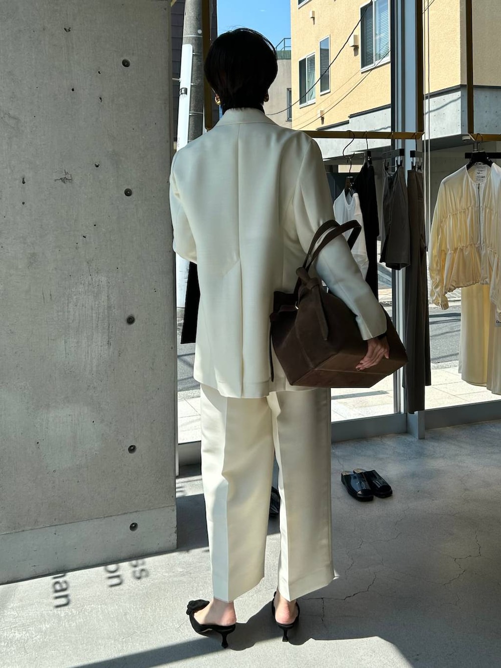 ブルー系のニット/セーター、ブラウン系のノーカラーコート、ホワイト系のテーラードジャケットを着用したレディースの秋コーディネートの5枚目の写真