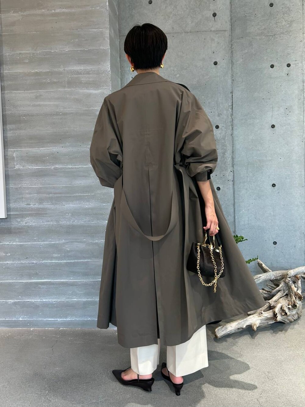 ホワイト系のスラックス、ブラウン系のトレンチコート、ブラウン系のその他アウターを着用したレディースの秋コーディネートの2枚目の写真