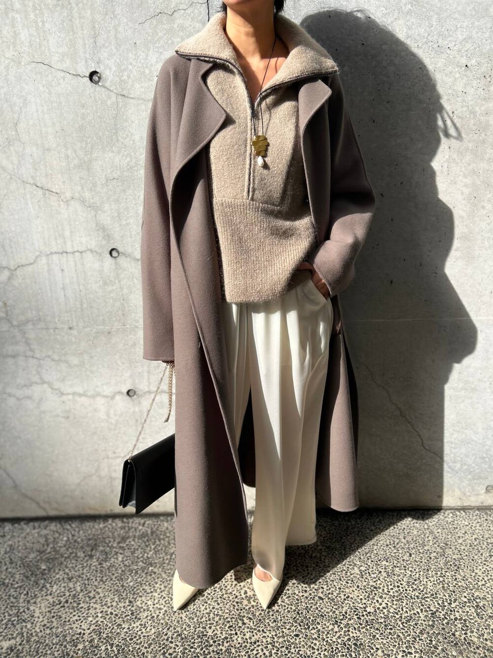 ブラウン系のノーカラーコート、ホワイト系のその他パンツ、ベージュ系のニット/セーターを着用したレディースの冬コーディネートの5枚目の写真