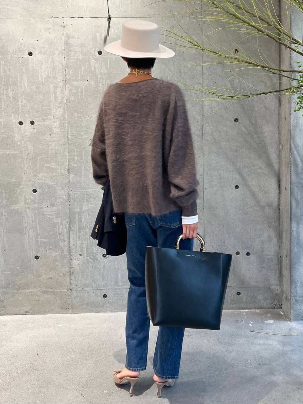 ブルー系のデニムパンツ、ブラウン系のニット/セーター、ホワイト系のTシャツ/カットソーを着用したレディースの秋コーディネートの2枚目の写真