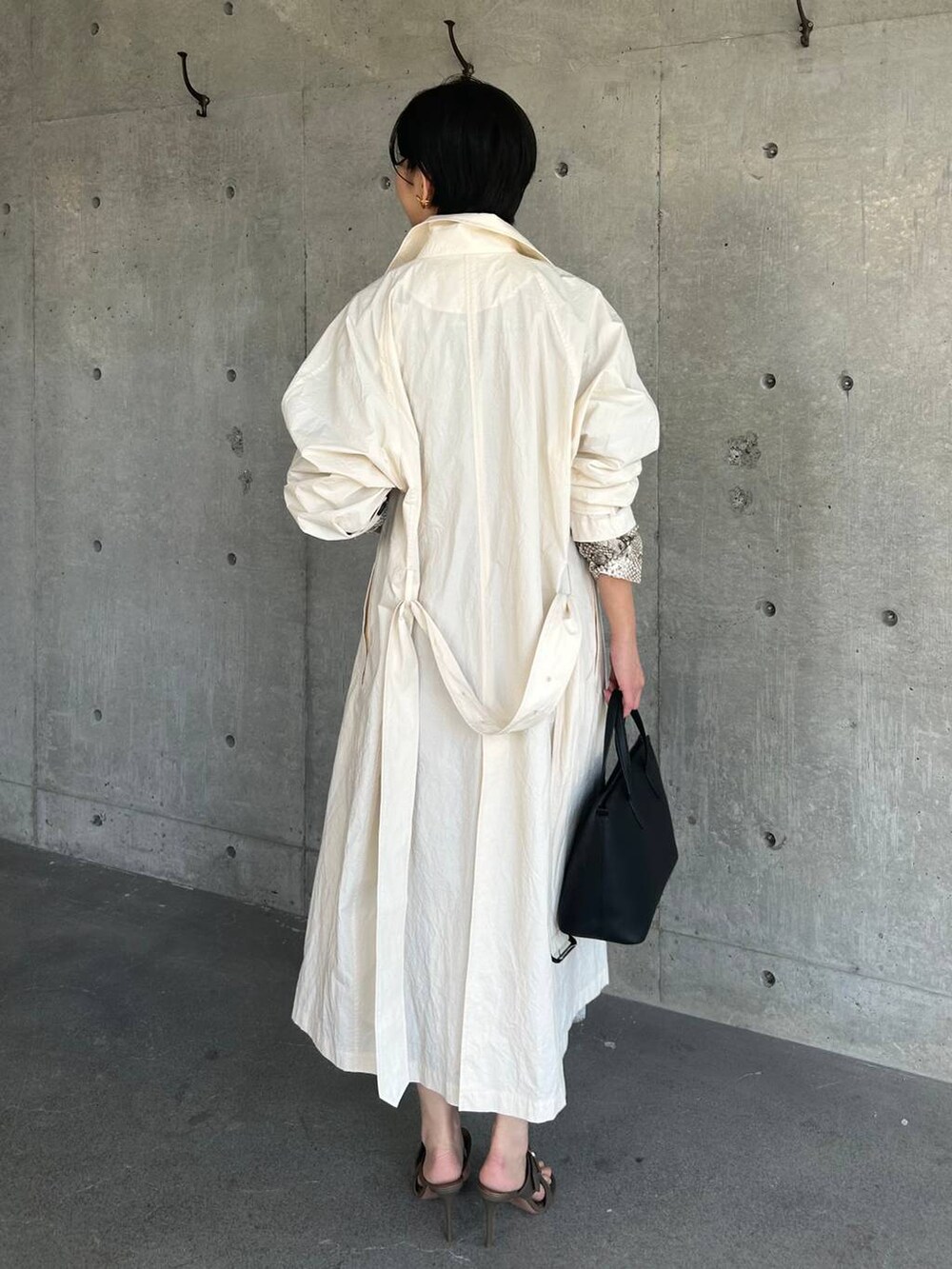 ホワイト系のステンカラーコート、ベージュ系のワンピースを着用したレディースの春コーディネートの7枚目の写真