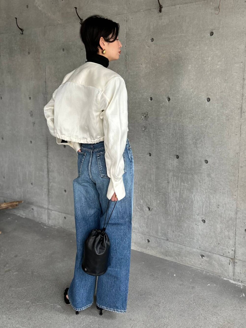 ブラック系のニット/セーター、ブルー系のデニムパンツ、ホワイト系のシャツ/ブラウスを着用したレディースの冬コーディネートの3枚目の写真