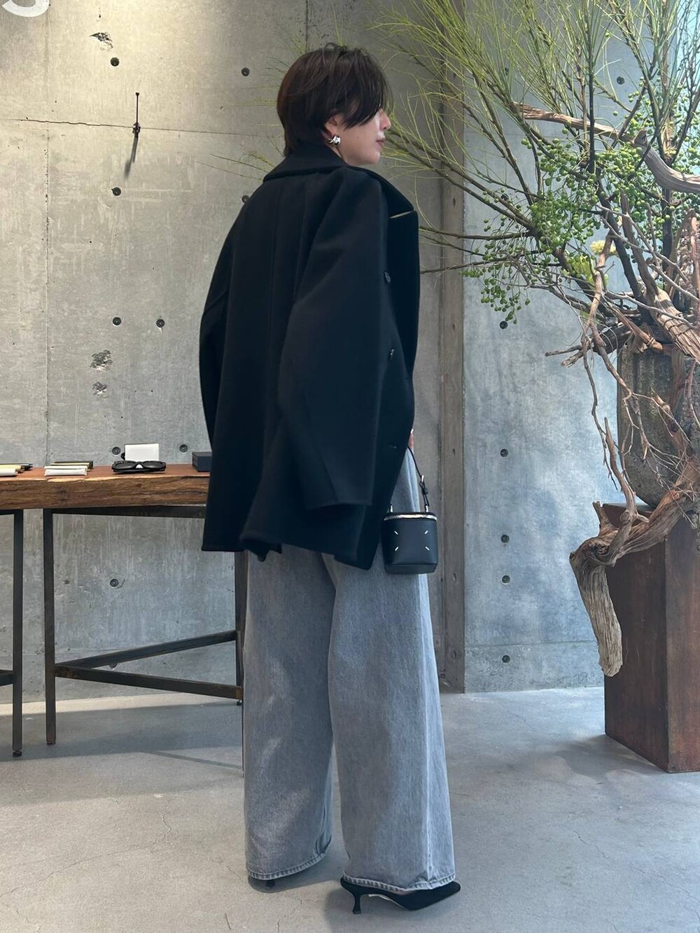 グレー系のデニムパンツ、ブラック系のピーコート、シルバー系のニット/セーターを着用したレディースの秋コーディネートの4枚目の写真