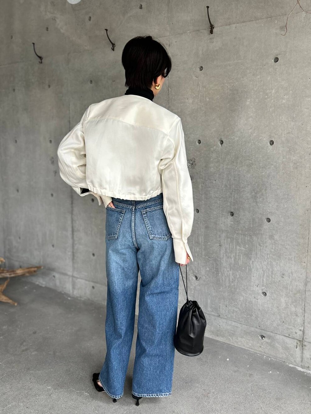 ブラック系のニット/セーター、ブルー系のデニムパンツ、ホワイト系のシャツ/ブラウスを着用したレディースの冬コーディネートの4枚目の写真