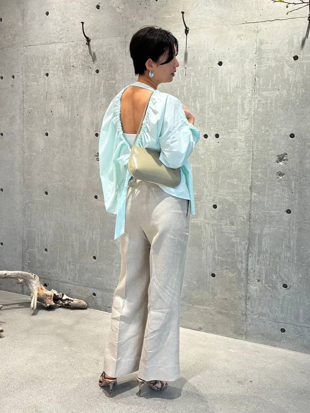 ホワイト系のスラックス、グレー系のナイロンジャケットを着用したレディースの春コーディネートの6枚目の写真