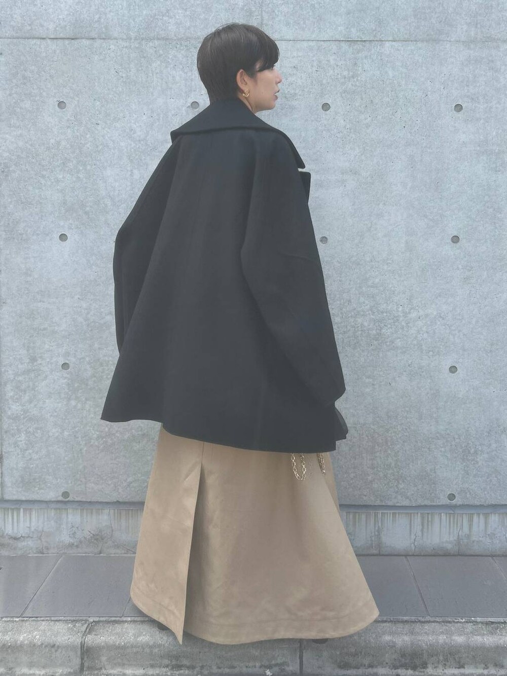 オレンジ系のTシャツ/カットソー、ベージュ系のスカート、ブラック系のその他アウターを着用したレディースの秋コーディネートの4枚目の写真