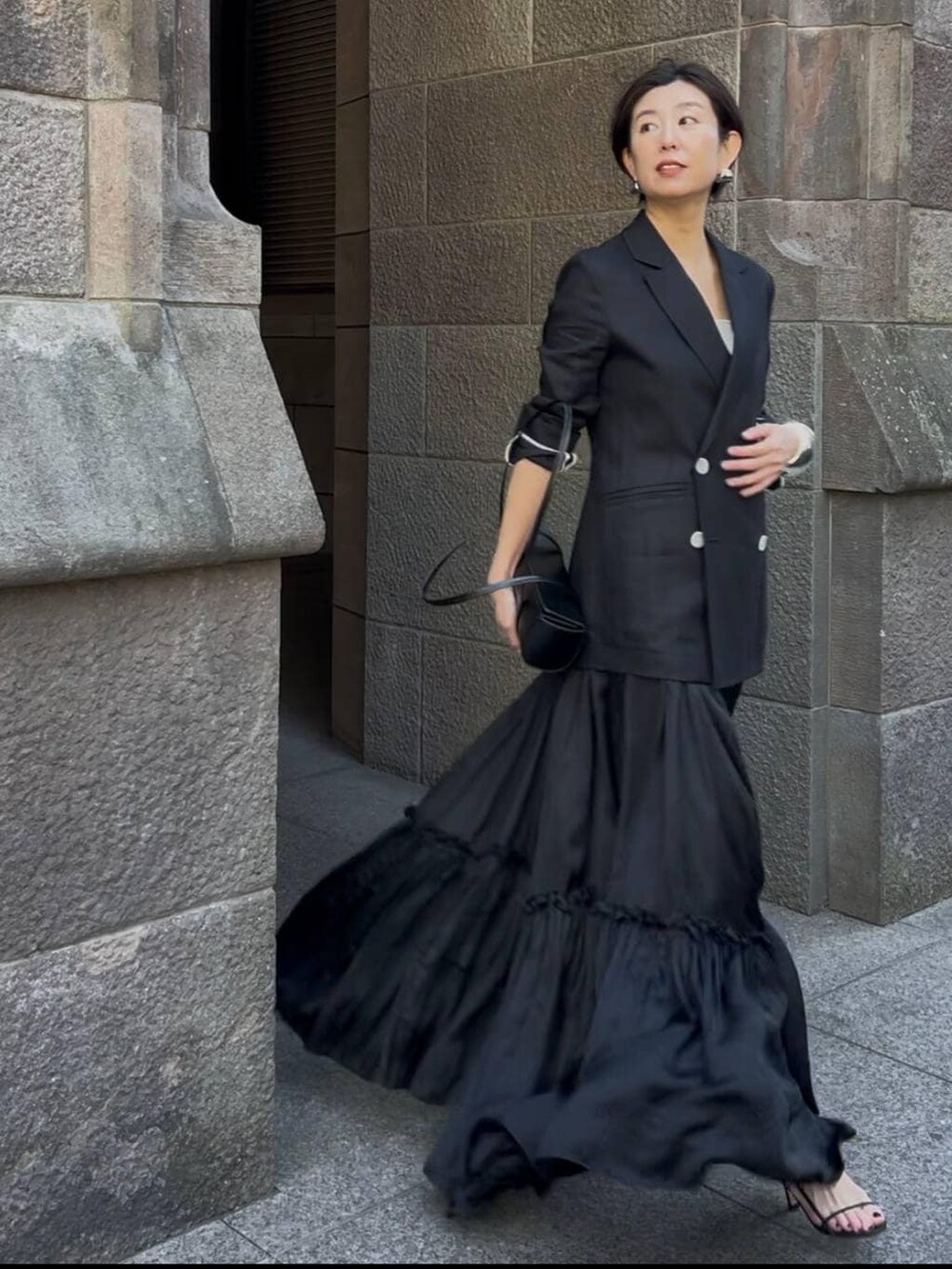 ベージュ系のタンクトップ、ブラック系のサンダル、ブラック系のテーラードジャケットを着用したレディースの冬コーディネートの2枚目の写真