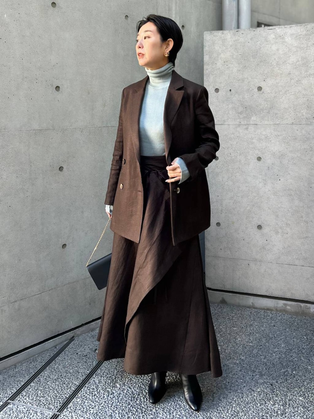 ブルー系のニット/セーター、ブラウン系のテーラードジャケット、ブラウン系のスカートを着用したレディースの冬コーディネートの2枚目の写真