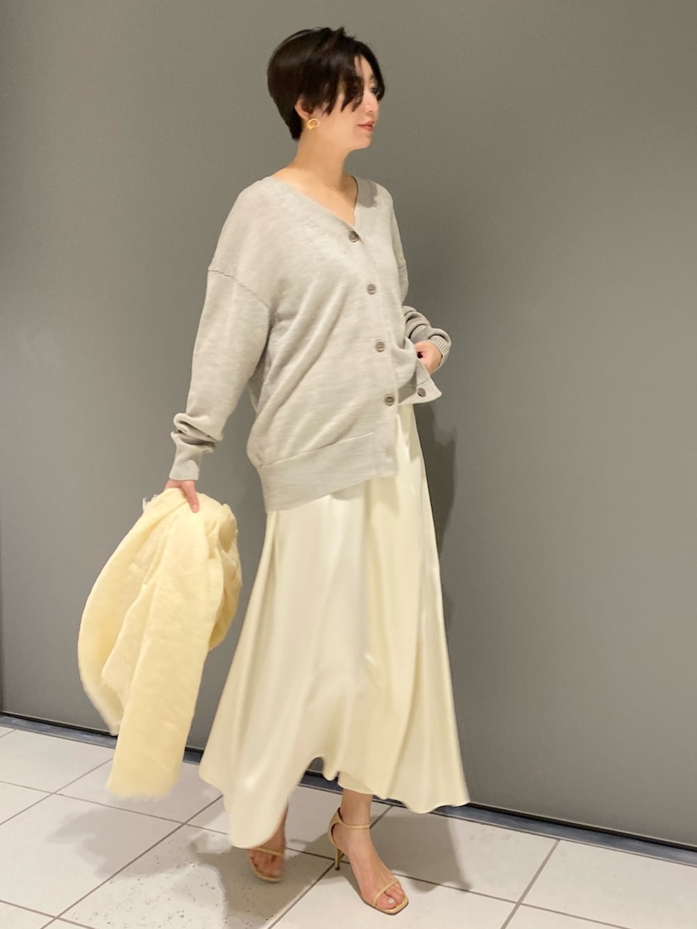 グレー系のカーディガン/ボレロ、ベージュ系のスカート、ベージュ系のストール/ショールを着用したレディースの冬コーディネートの2枚目の写真