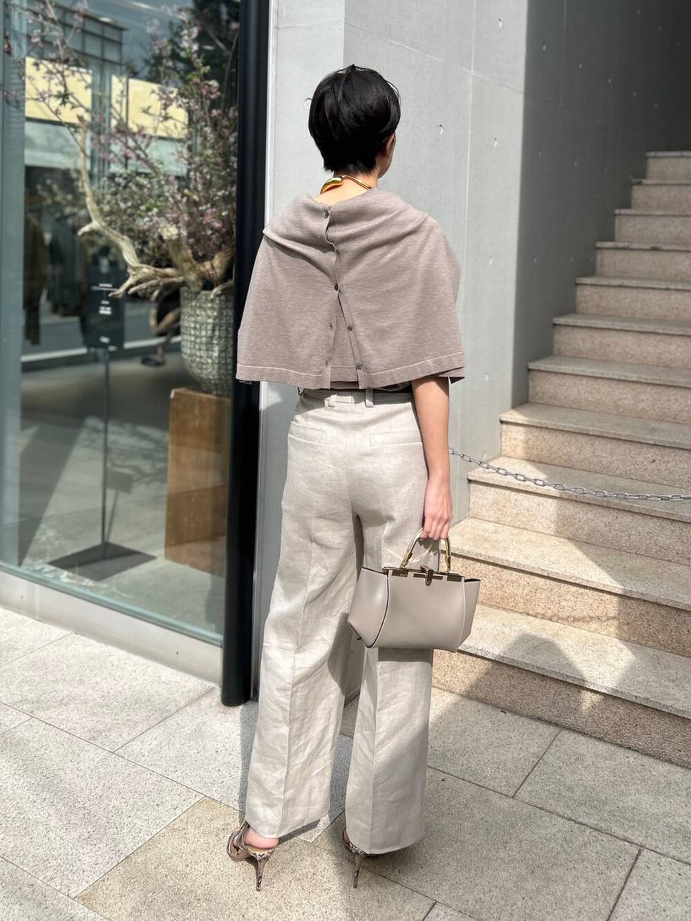 ホワイト系のスラックス、ブラウン系のニット/セーター、ブラウン系のカーディガン/ボレロを着用したレディースの春コーディネートの4枚目の写真