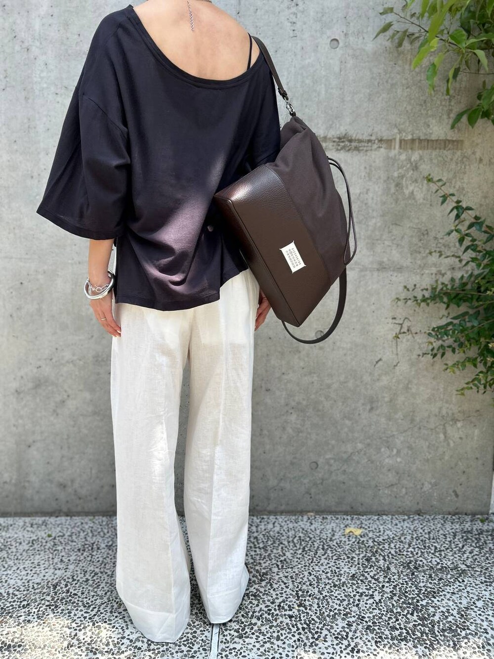 ブラック系のチューブトップ、ホワイト系のスラックス、グレー系のTシャツ/カットソーを着用したレディースの春コーディネートの8枚目の写真