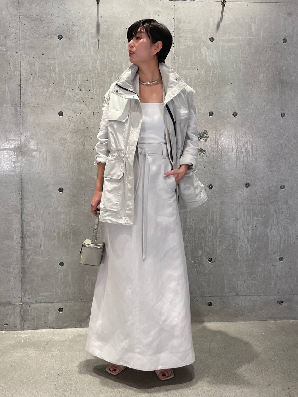 ホワイト系のタンクトップ、グレー系のベスト、ベージュ系のサンダルを着用したレディースの春コーディネートの6枚目の写真