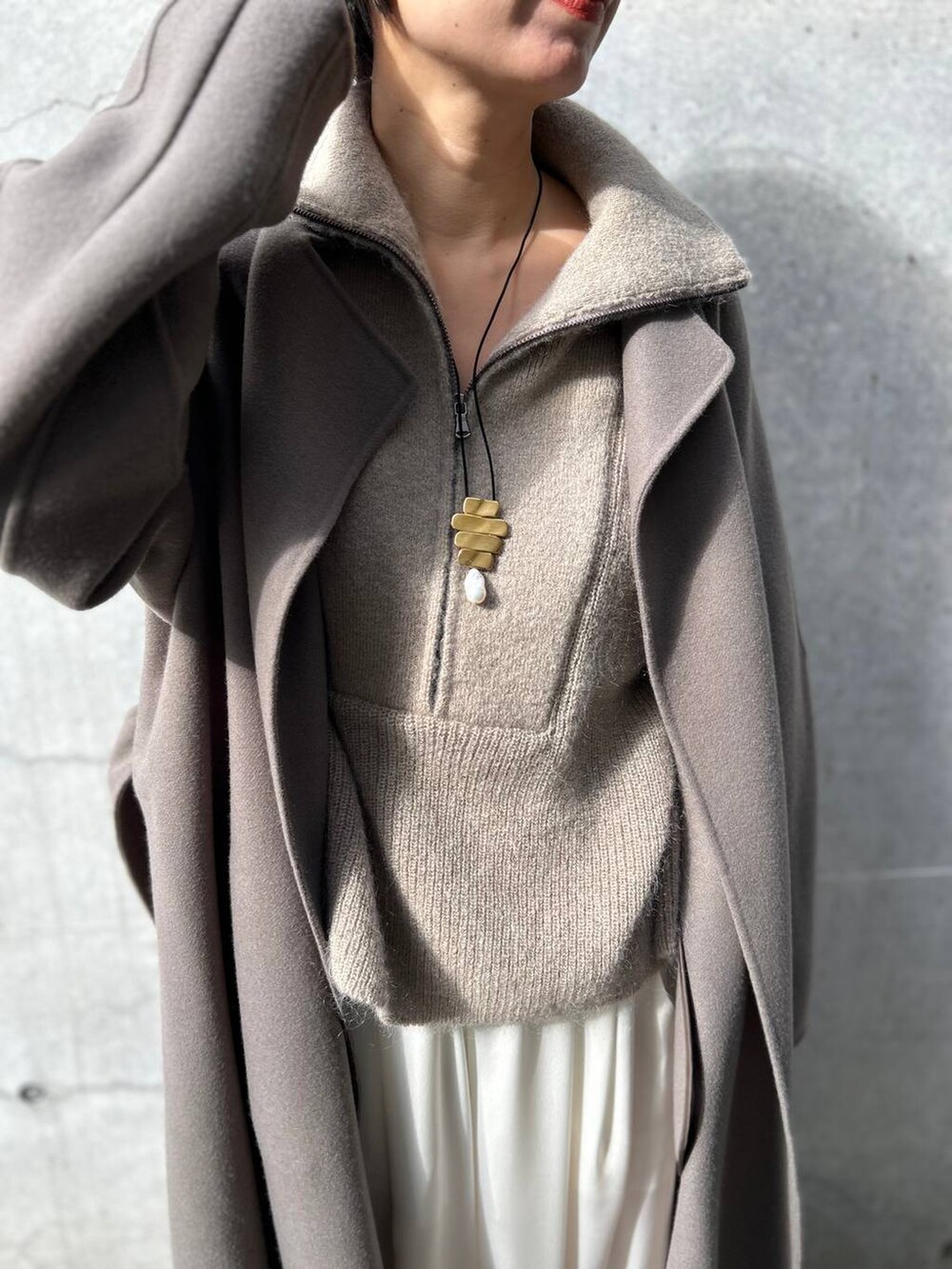 ブラウン系のノーカラーコート、ホワイト系のその他パンツ、ベージュ系のニット/セーターを着用したレディースの冬コーディネートの6枚目の写真