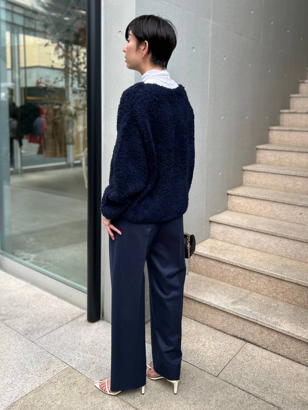 ブルー系のニット/セーター、ホワイト系のその他トップス、ブルー系のスラックスを着用したレディースの秋コーディネートの4枚目の写真