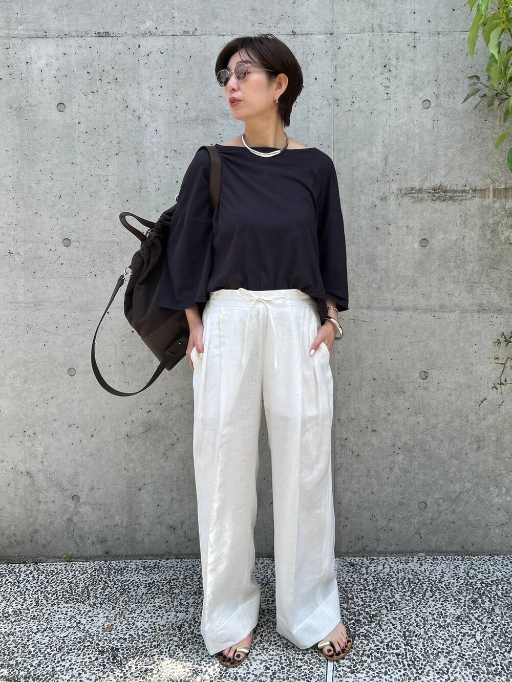 ブラック系のチューブトップ、ホワイト系のスラックス、グレー系のTシャツ/カットソーを着用したレディースの春コーディネートの2枚目の写真