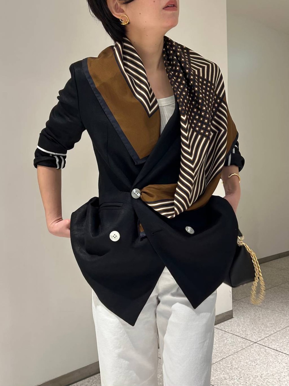 ホワイト系のデニムパンツ、ホワイト系のタンクトップ、ブラック系のテーラードジャケットを着用したレディースの春コーディネートの5枚目の写真