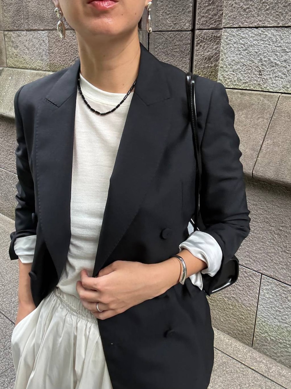 ベージュ系のスカート、ホワイト系のTシャツ/カットソー、ブラック系のテーラードジャケットを着用したレディースの夏コーディネートの6枚目の写真
