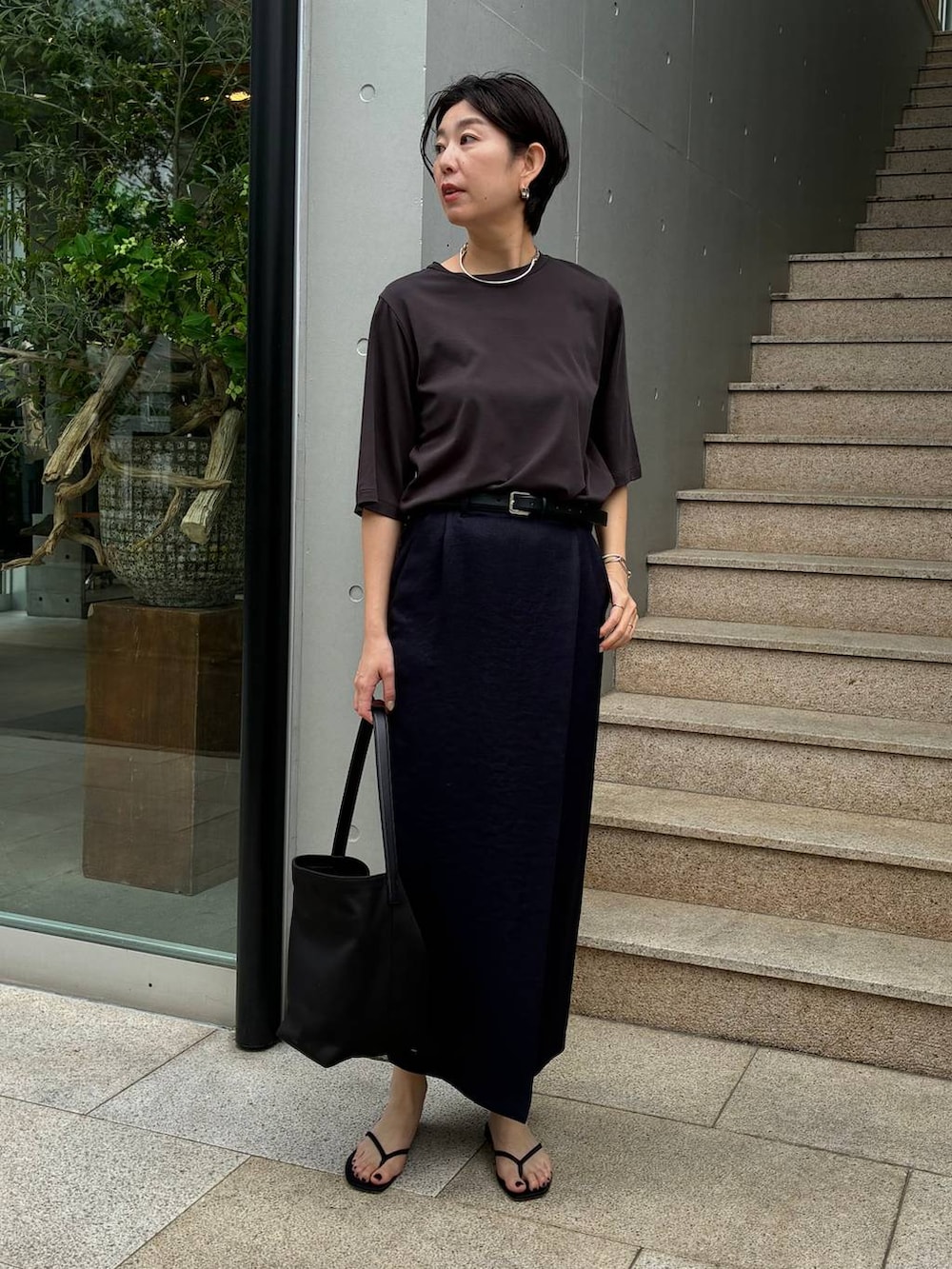 ブルー系のスカート、ブラック系のサンダル、ブラウン系のTシャツ/カットソーを着用したレディースの春コーディネートの2枚目の写真