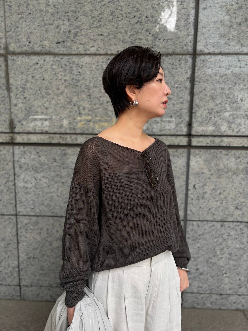 グリーン系のニット/セーター、ホワイト系のスラックス、グレー系のナイロンジャケットを着用したレディースの春コーディネートの7枚目の写真