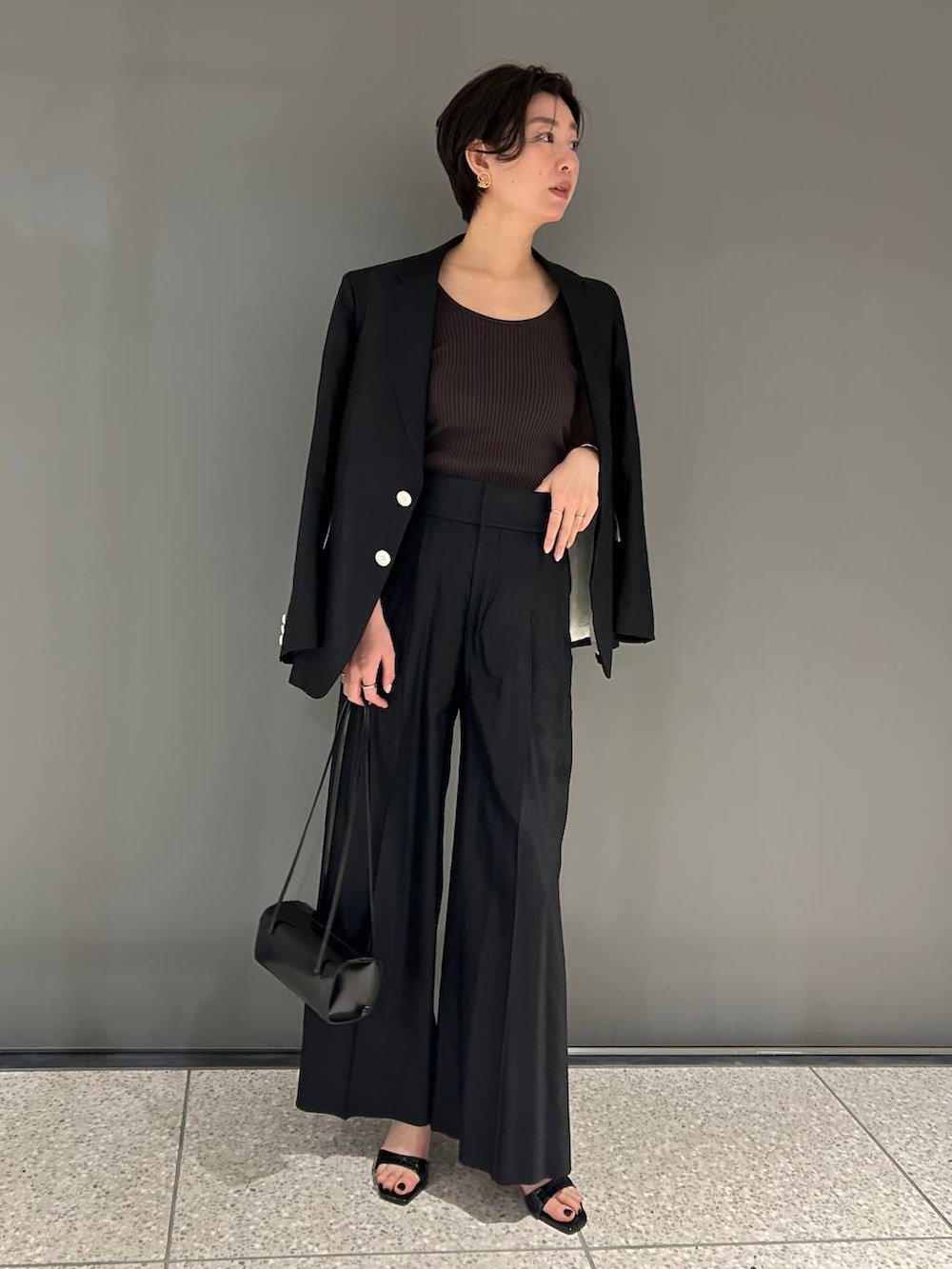 ブラック系のスラックス、ブラック系のテーラードジャケットを着用したレディースの春コーディネートの2枚目の写真