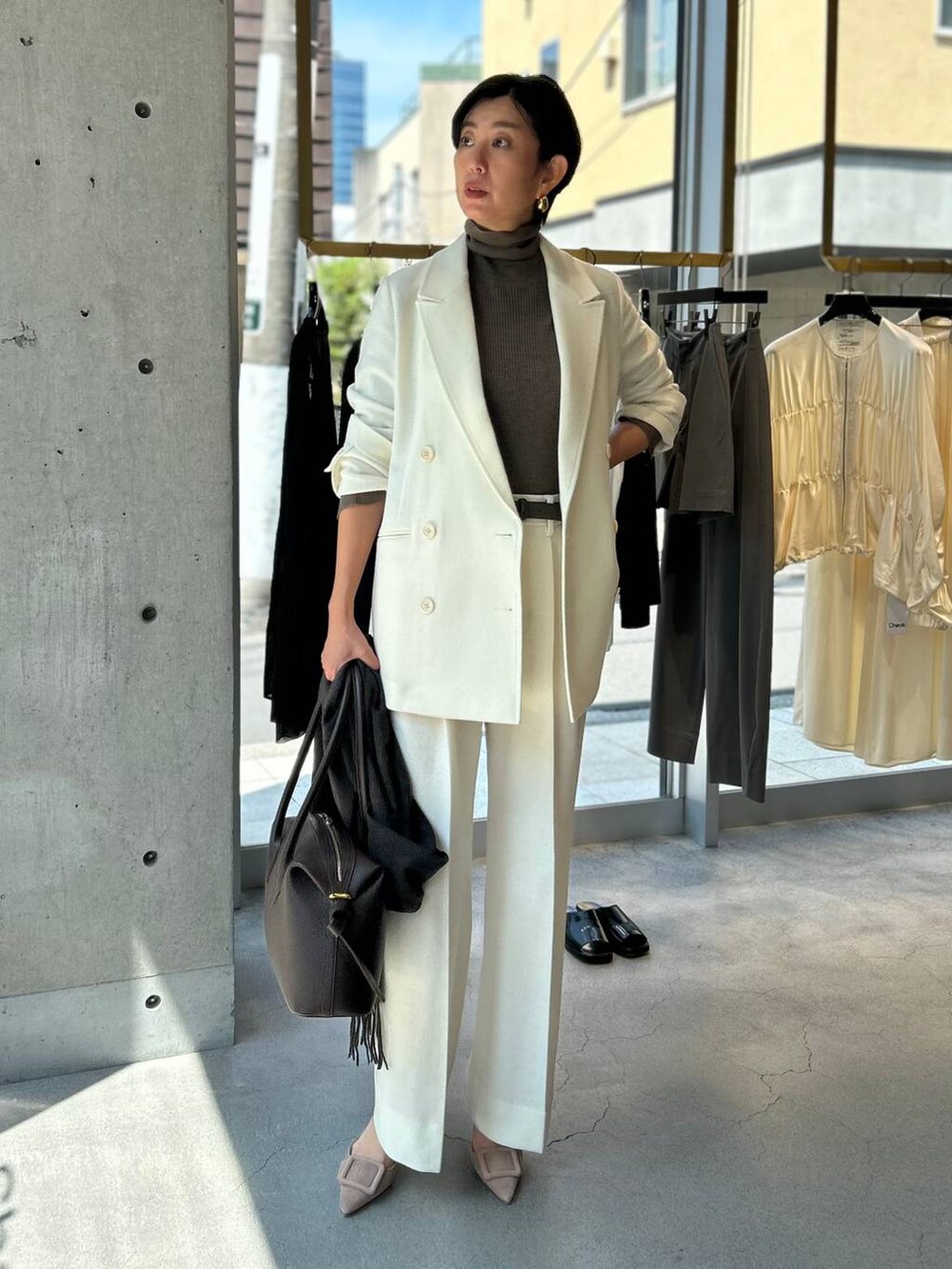 ベージュ系のニット/セーター、ホワイト系のスラックス、ホワイト系のテーラードジャケットを着用したレディースの秋コーディネートの2枚目の写真