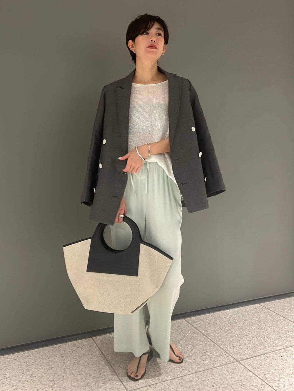 グリーン系のその他パンツ、ホワイト系のニット/セーター、ブラック系のテーラードジャケットを着用したレディースの春コーディネートの2枚目の写真