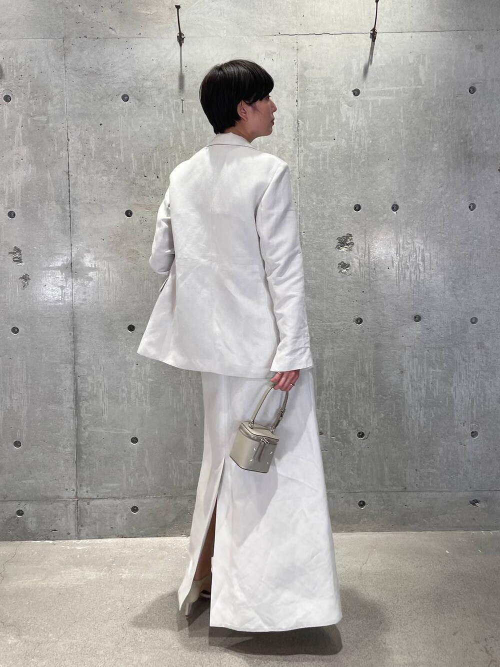 ホワイト系のタンクトップ、グレー系のベスト、ベージュ系のサンダルを着用したレディースの春コーディネートの5枚目の写真