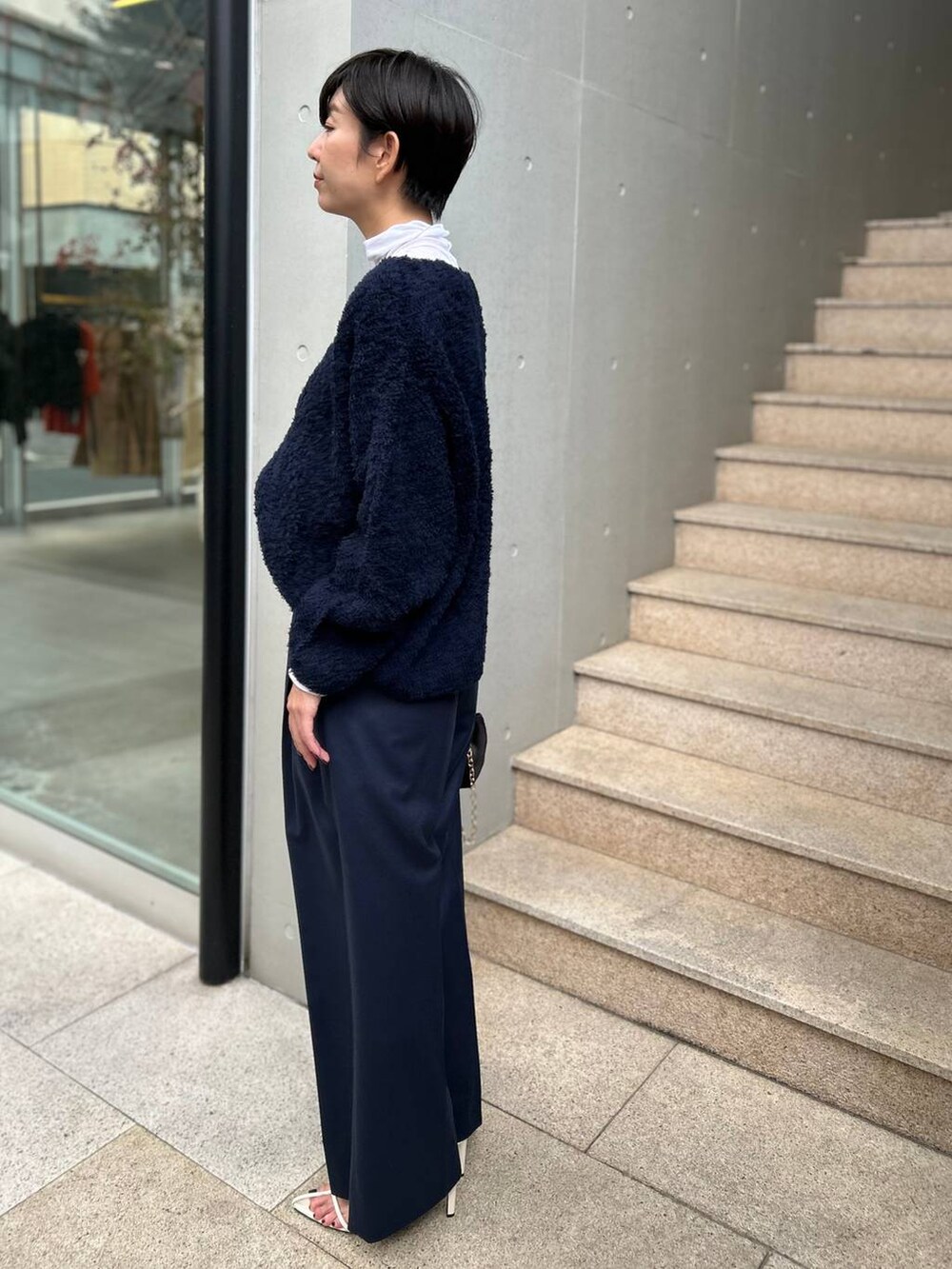 ブルー系のニット/セーター、ホワイト系のその他トップス、ブルー系のスラックスを着用したレディースの秋コーディネートの3枚目の写真