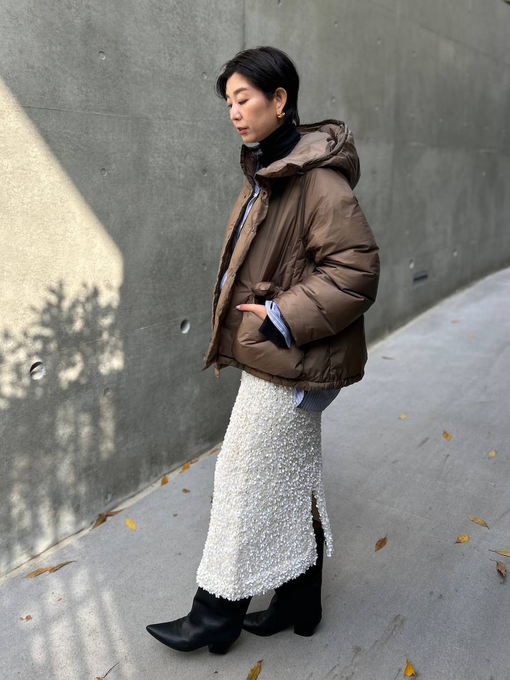 ブラック系のニット/セーター、ブルー系のシャツ/ブラウス、ブラウン系のダウンジャケット/コートを着用したレディースの冬コーディネートの4枚目の写真