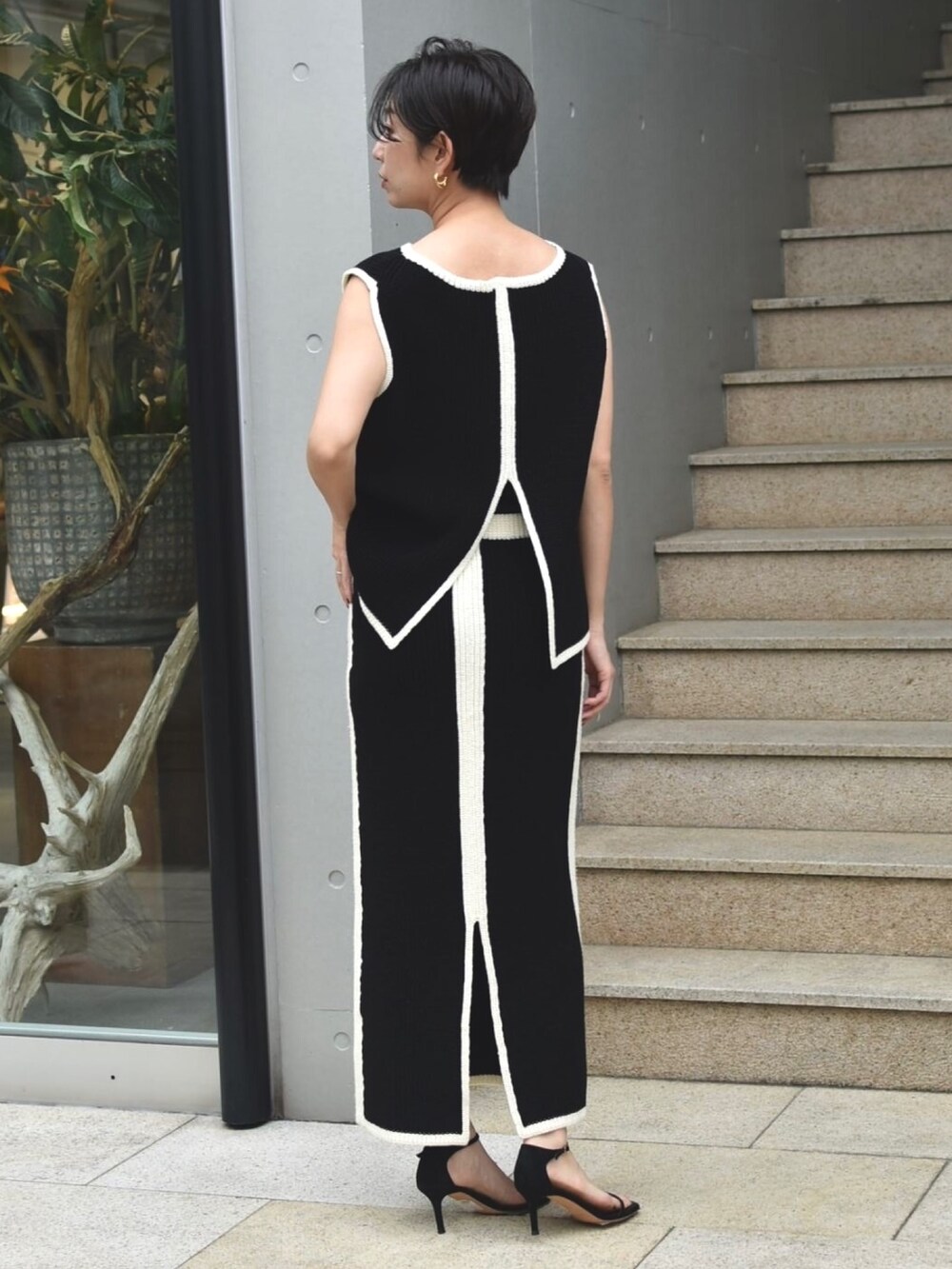 ブラック系のニット/セーター、ブラック系のスカート、ブラック系のサンダルを着用したレディースの夏コーディネートの3枚目の写真