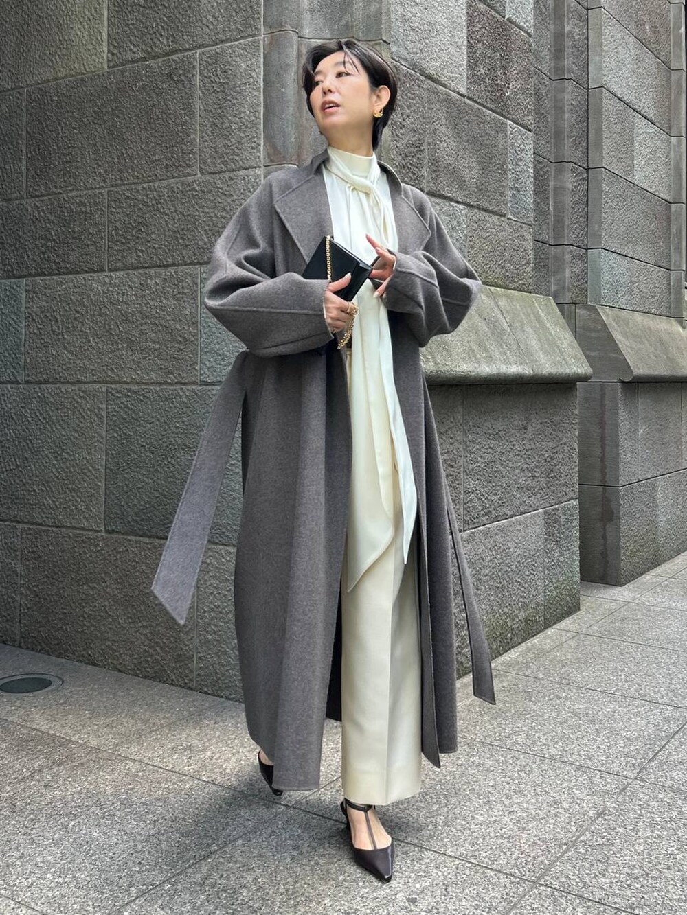 ブラウン系のノーカラーコート、ホワイト系のスラックス、ホワイト系のシャツ/ブラウスを着用したレディースの秋コーディネートの2枚目の写真