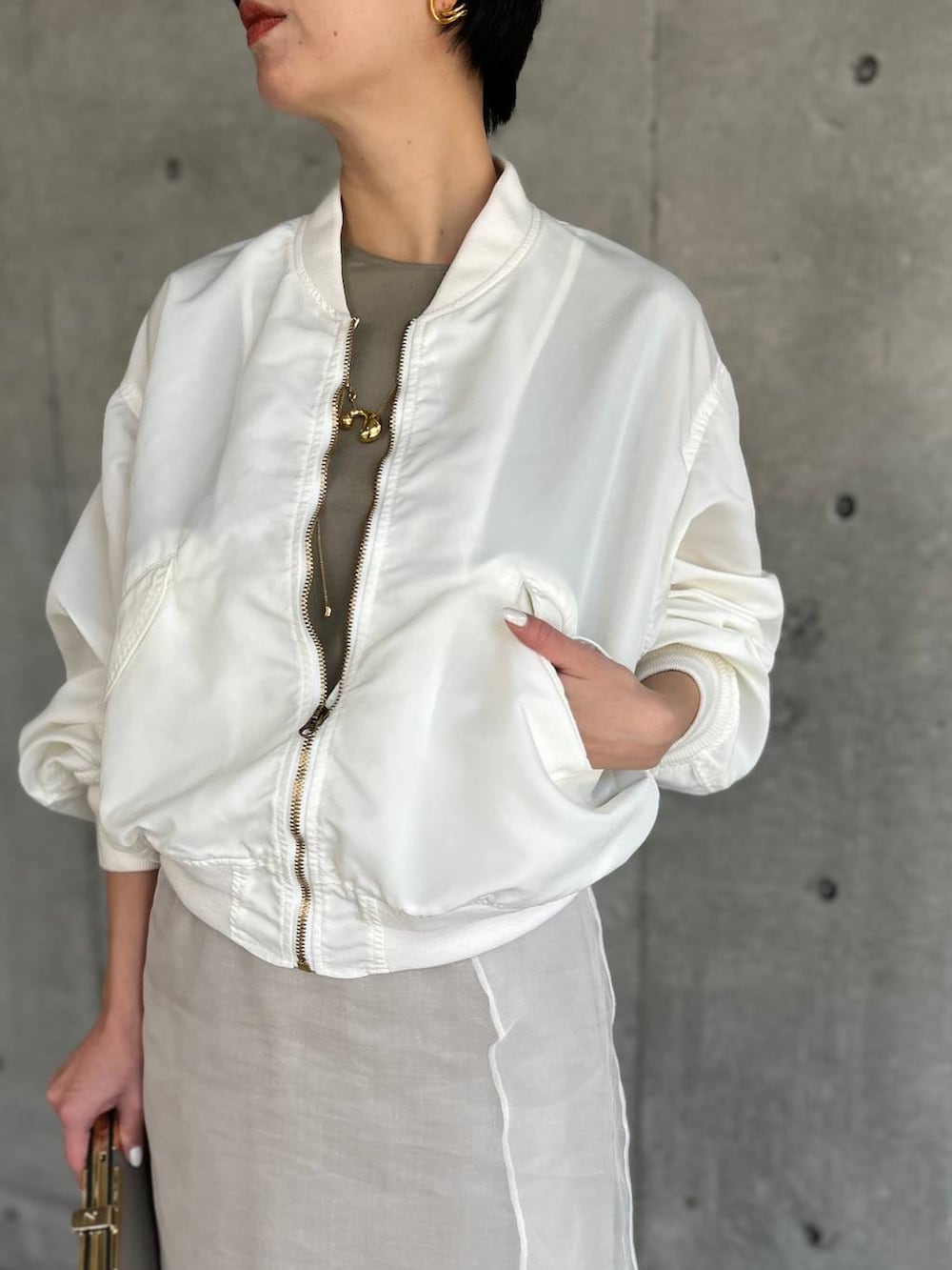 ベージュ系のスカート、ホワイト系のMA-1を着用したレディースの春コーディネートの6枚目の写真