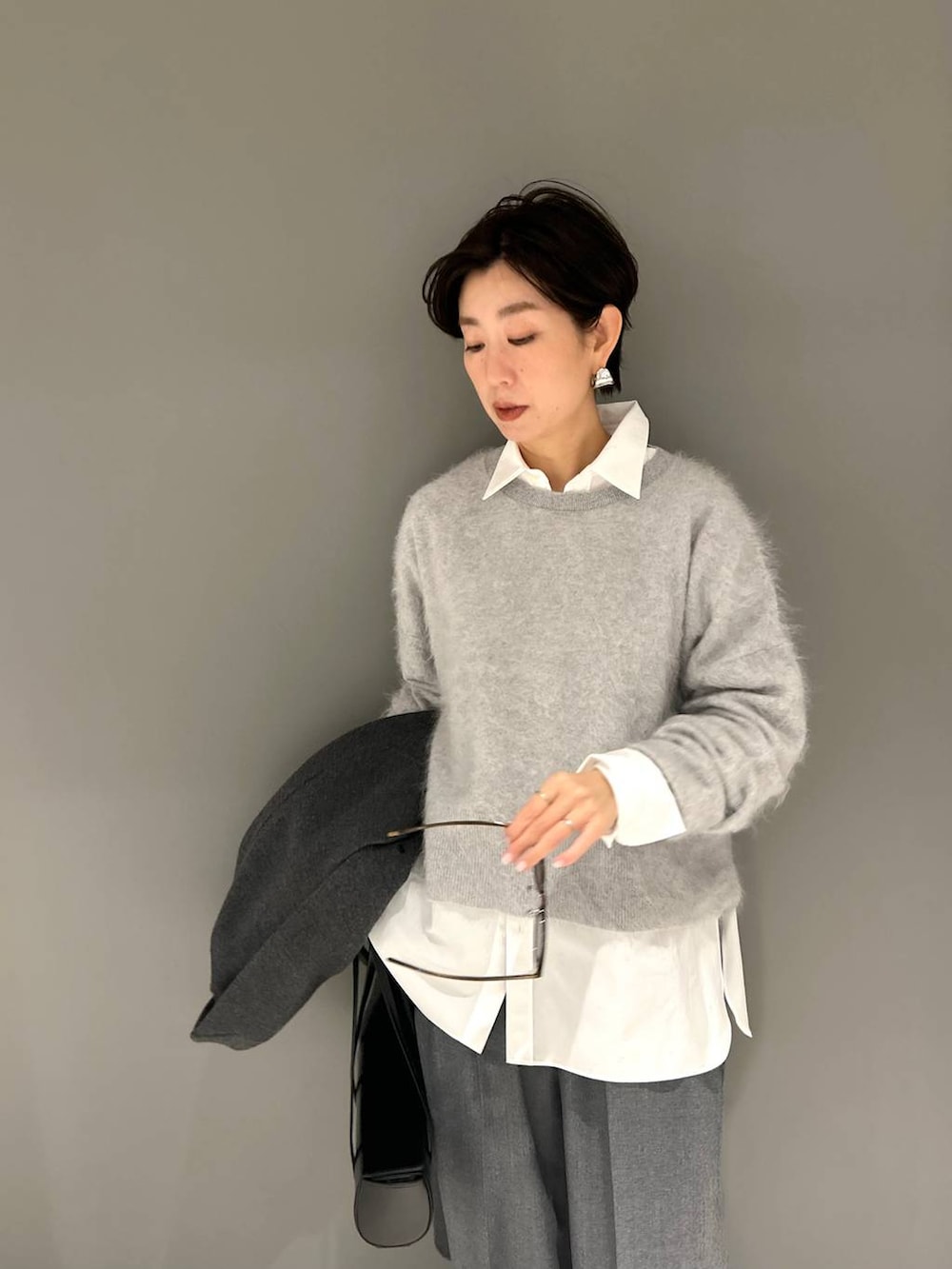 グレー系のニット/セーター、ホワイト系のシャツ/ブラウス、グレー系のスラックスを着用したレディースの秋コーディネートの7枚目の写真