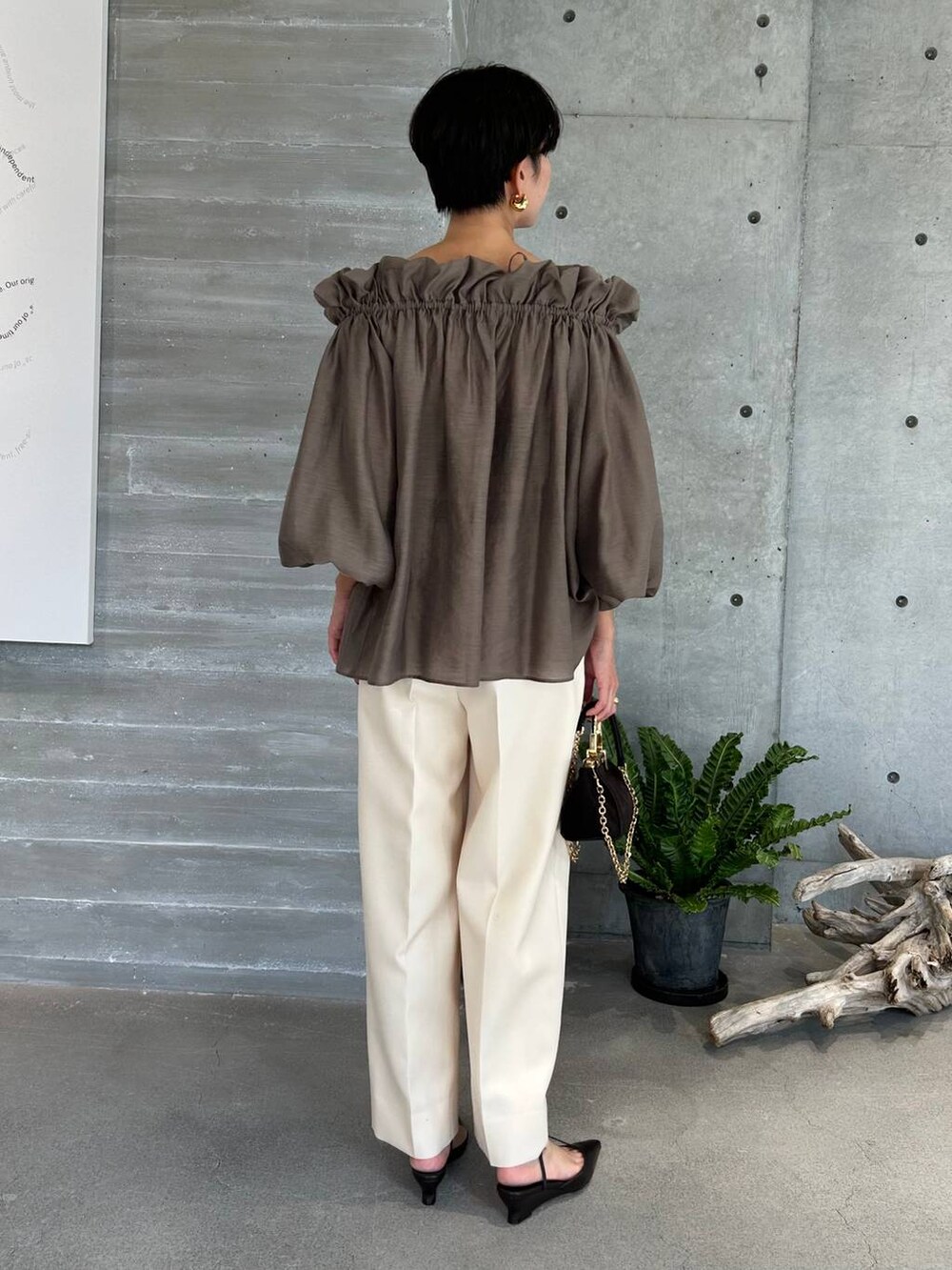 ホワイト系のスラックス、ブラウン系のトレンチコート、ブラウン系のその他アウターを着用したレディースの秋コーディネートの5枚目の写真