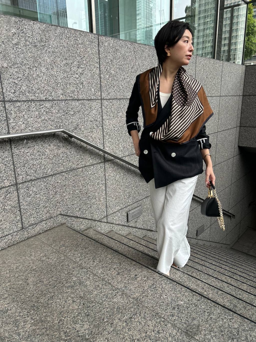 ホワイト系のデニムパンツ、ホワイト系のタンクトップ、ブラック系のテーラードジャケットを着用したレディースの春コーディネートの6枚目の写真