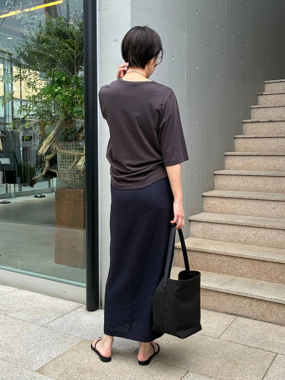 ブルー系のスカート、ブラック系のサンダル、ブラウン系のTシャツ/カットソーを着用したレディースの春コーディネートの4枚目の写真