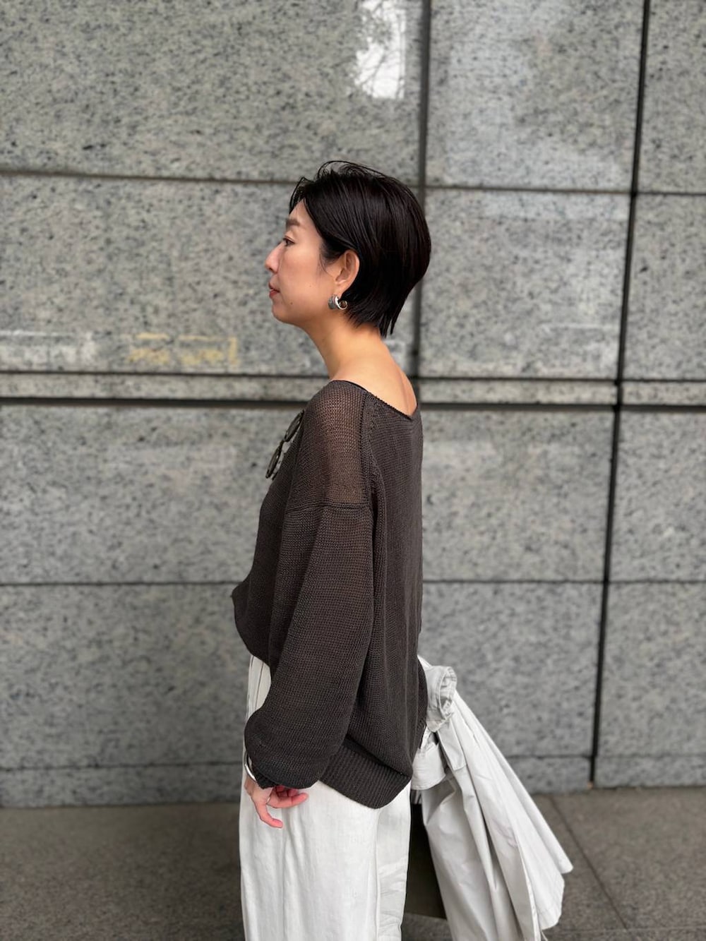 グリーン系のニット/セーター、ホワイト系のスラックス、グレー系のナイロンジャケットを着用したレディースの春コーディネートの8枚目の写真