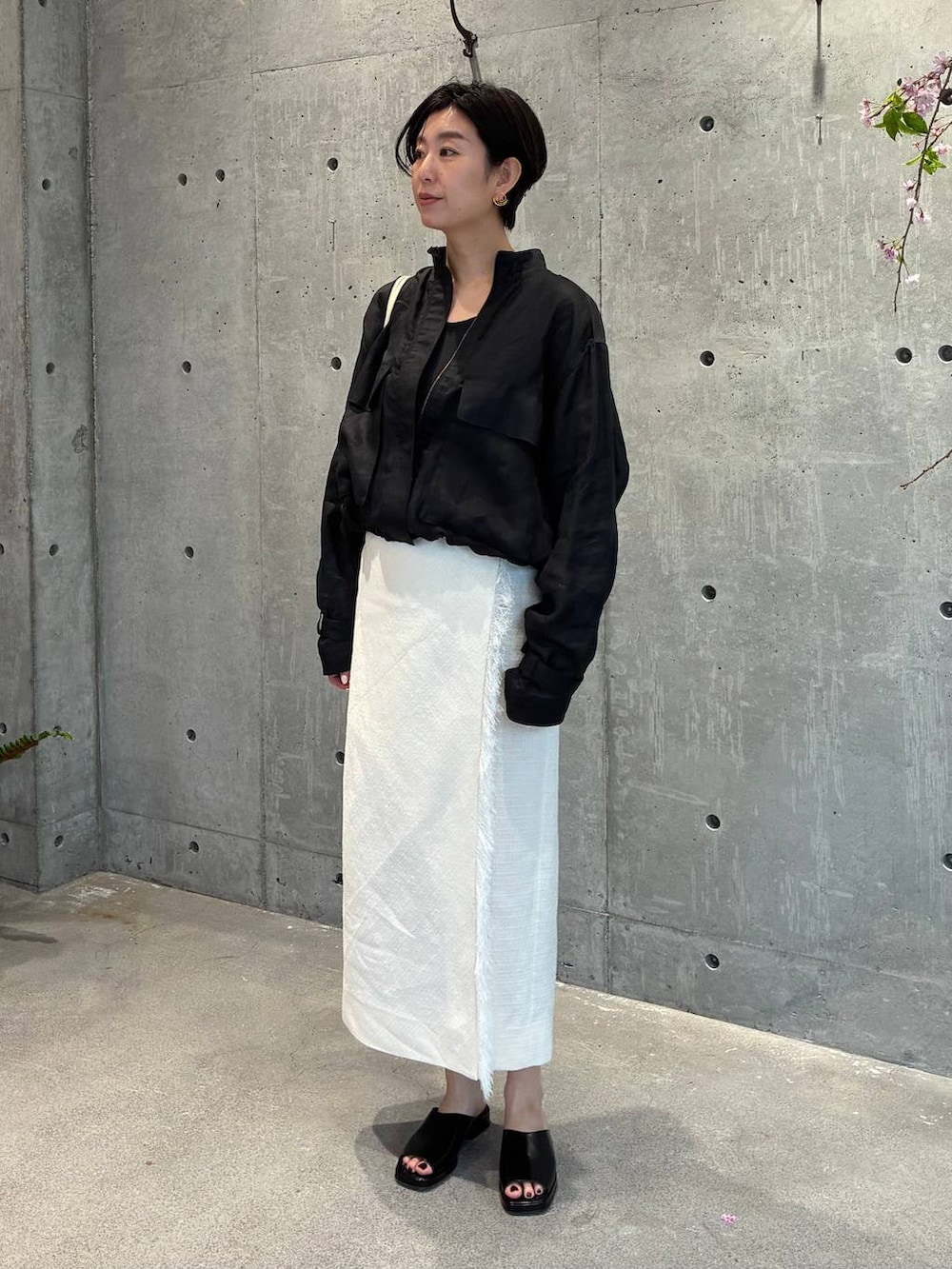 ブラック系のシャツ/ブラウス、ブラック系のブルゾン、ホワイト系のスカートを着用したレディースの春コーディネートの2枚目の写真