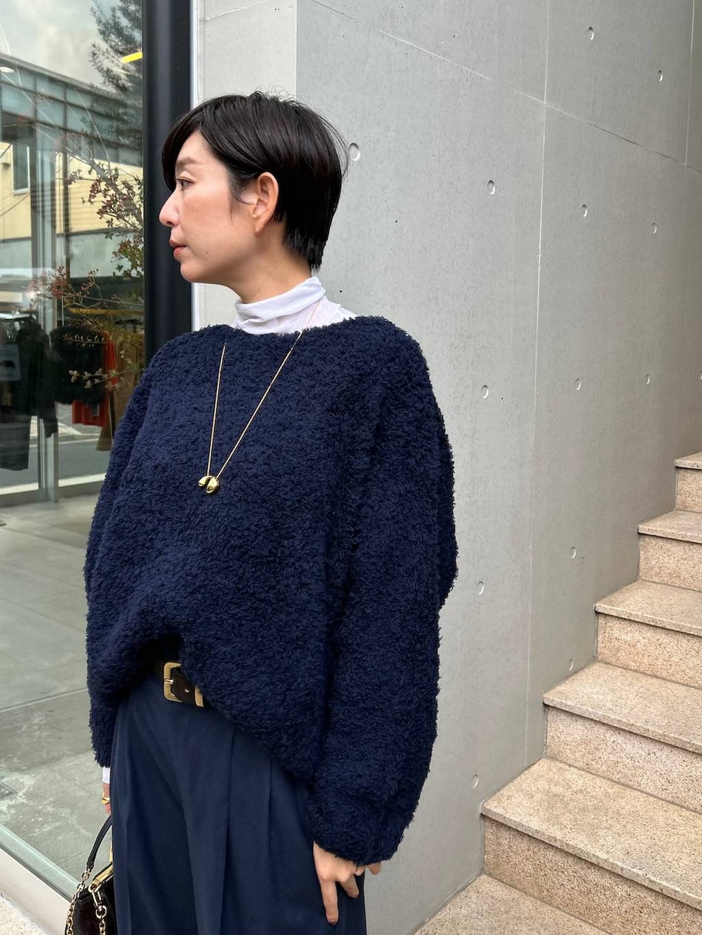 ブルー系のニット/セーター、ホワイト系のその他トップス、ブルー系のスラックスを着用したレディースの秋コーディネートの6枚目の写真