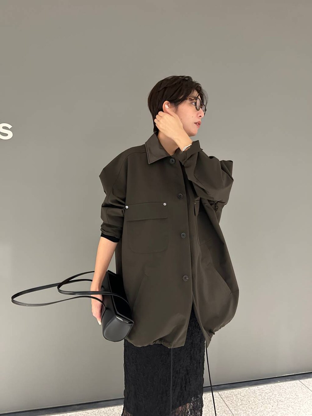 ブラック系のTシャツ/カットソー、ブラウン系のステンカラーコート、ブラック系のスカートを着用したレディースの夏コーディネートの6枚目の写真
