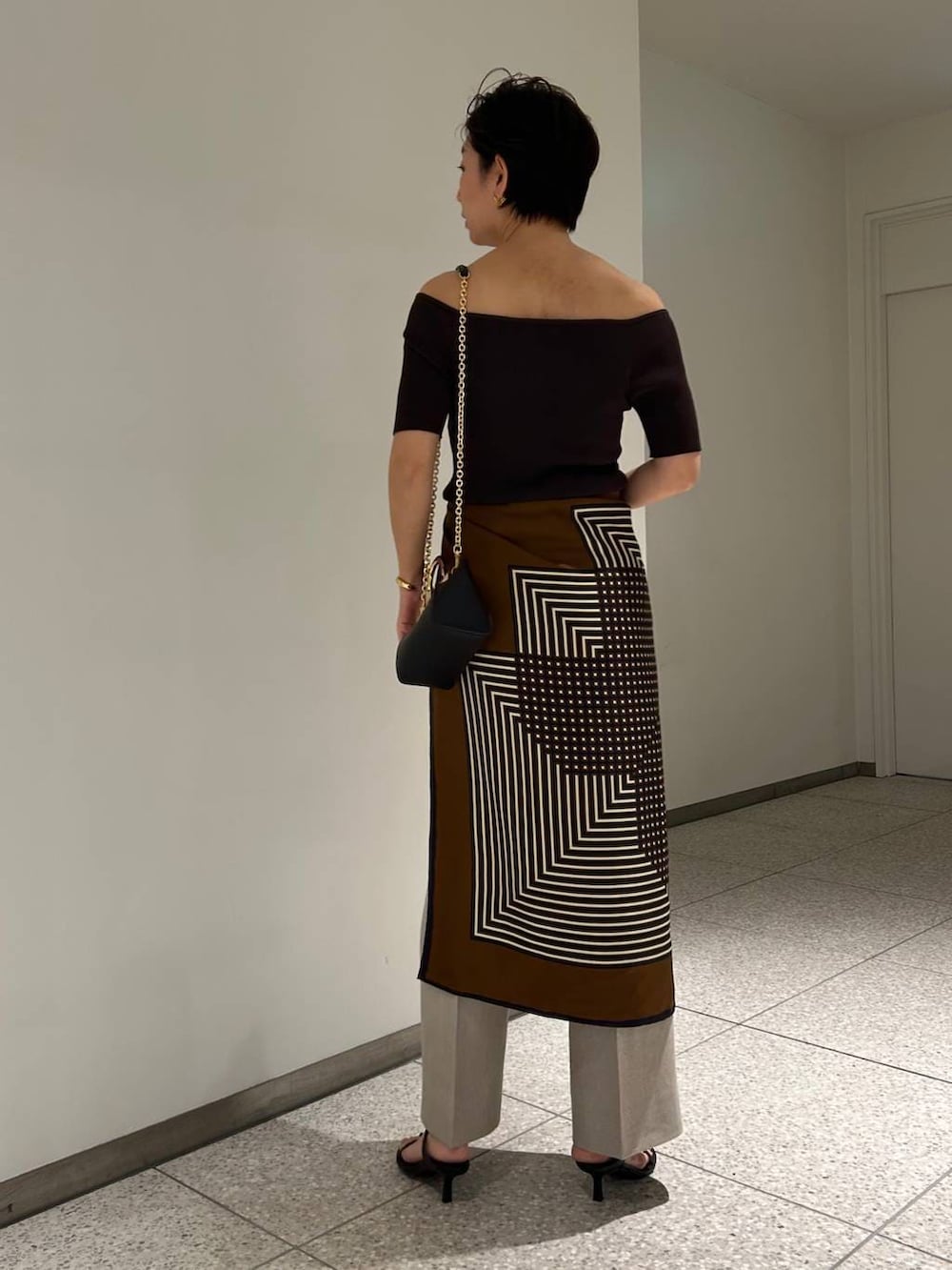 ホワイト系のスラックス、ブラウン系のTシャツ/カットソー、ブラウン系のバンダナ/スカーフを着用したレディースの春コーディネートの5枚目の写真