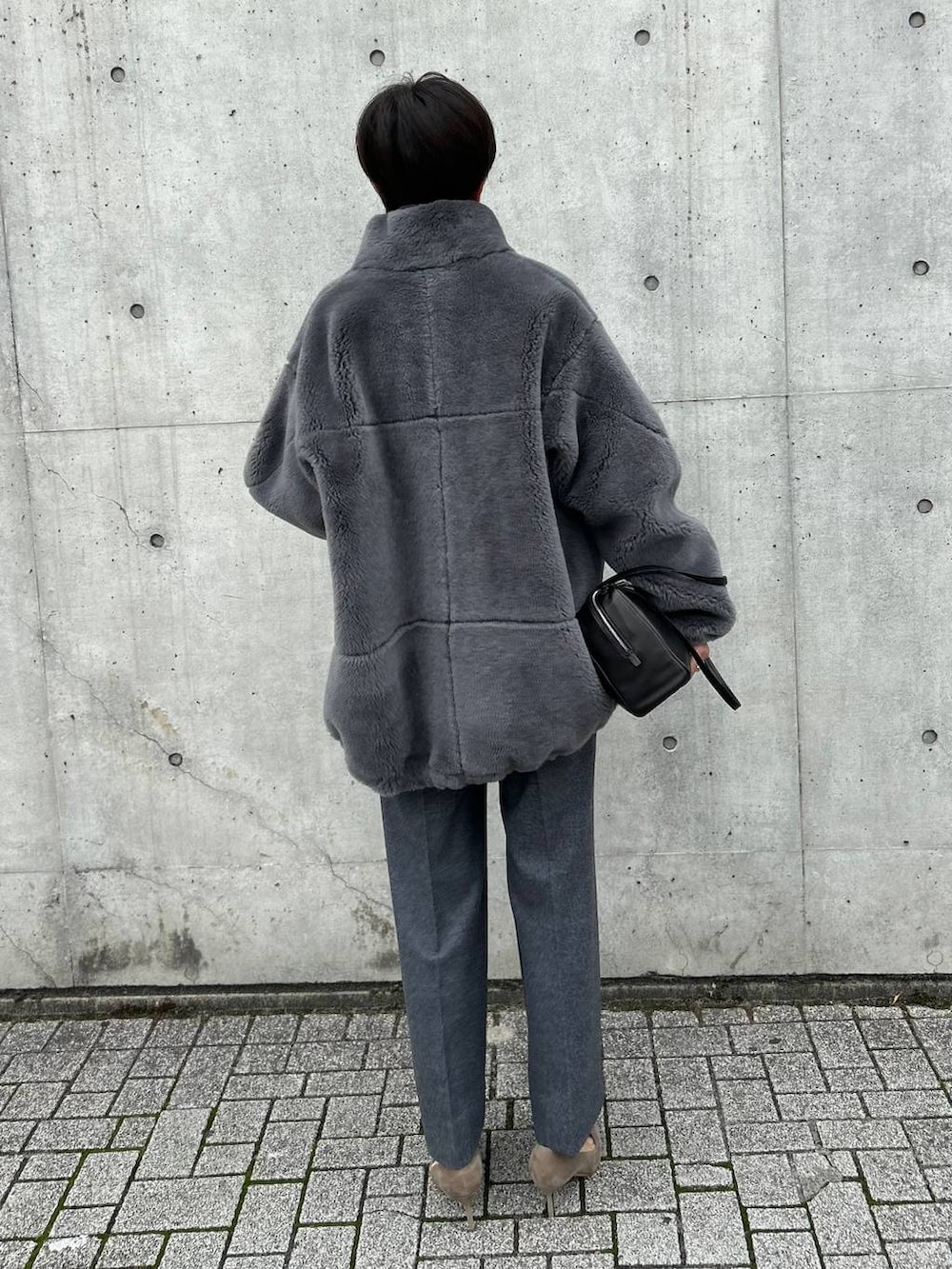 ブラック系のニット/セーター、グレー系のブルゾン、ホワイト系のスラックスを着用したレディースの秋コーディネートの3枚目の写真