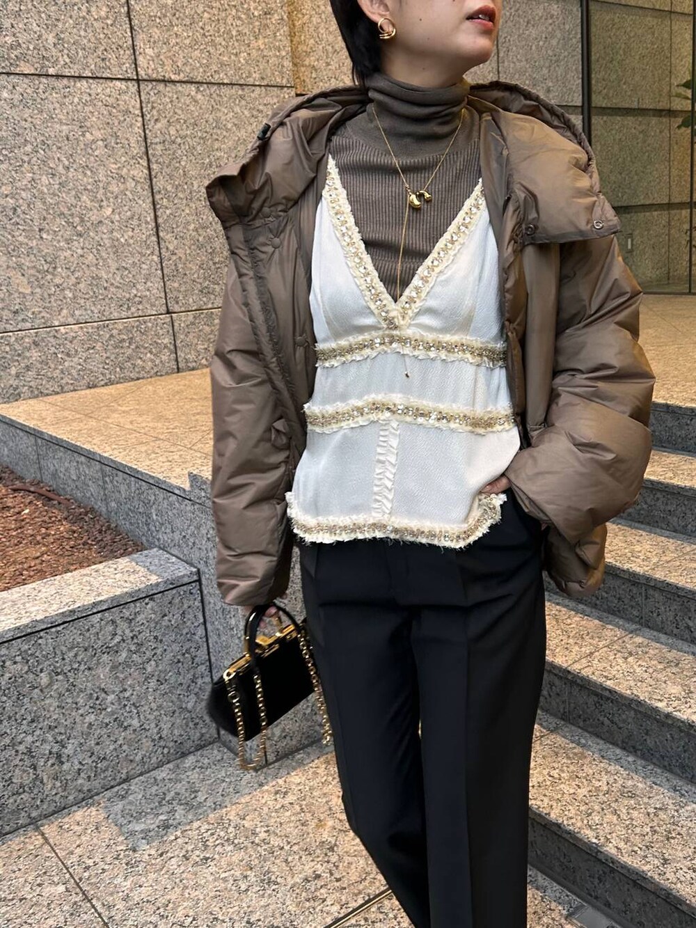 ベージュ系のニット/セーター、ブラウン系のダウンジャケット/コート、ブラック系のスラックスを着用したレディースの冬コーディネートの7枚目の写真