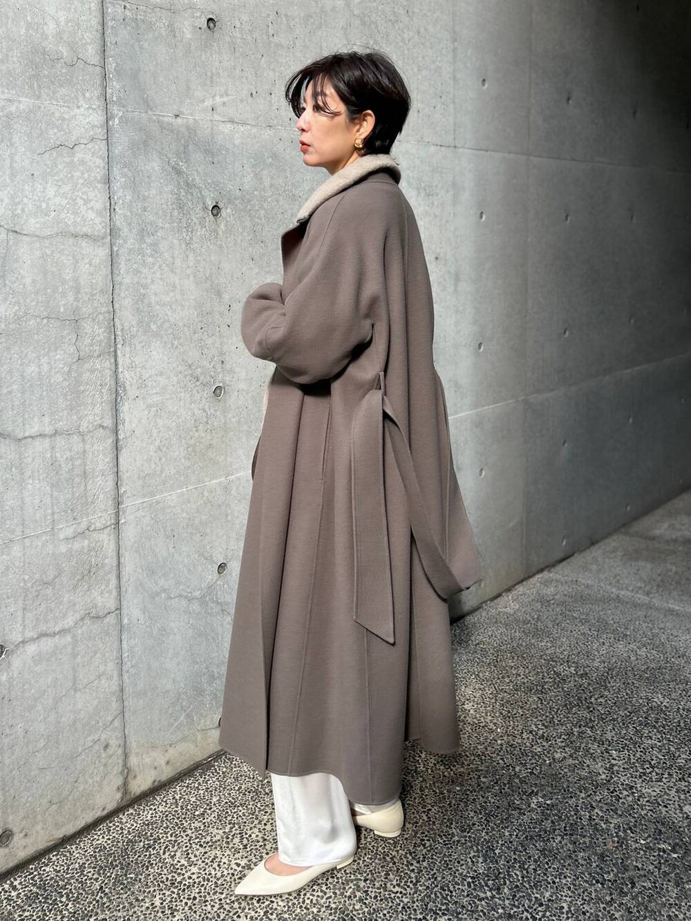 ブラウン系のノーカラーコート、ホワイト系のその他パンツ、ベージュ系のニット/セーターを着用したレディースの冬コーディネートの3枚目の写真